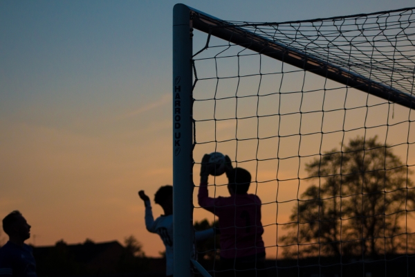 friends playing football in front of a goal